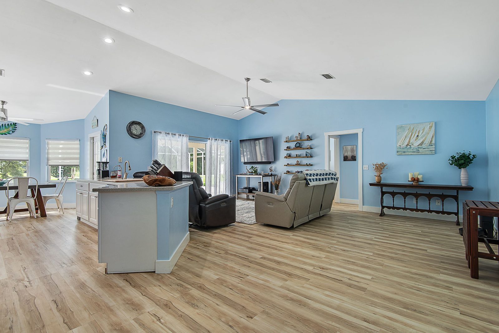 Open-concept living, dining, and kitchen with vaulted ceilings and luxury vinyl plank flooring